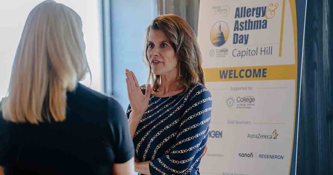 Allergy & Asthma Day Capitol Hill 2025: Leading the Charge Amid Federal Policy Shifts 29 Two women talk in front of a sign that reads “Allergy & Asthma Day on Capitol Hill” with sponsor logos below. One woman gestures with her hand while speaking.