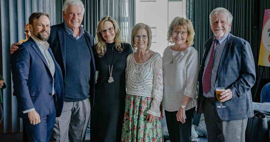 Allergy & Asthma Day Capitol Hill 2025: Leading the Charge Amid Federal Policy Shifts 22 Six adults, three men and three women, stand closely together indoors, smiling at the camera. The group is dressed in business and semi-formal attire. One man holds a glass of wine. Curtains and a window are in the background.