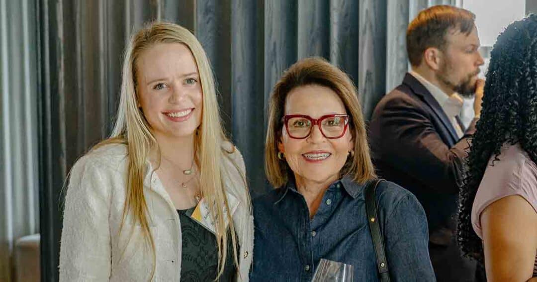 Allergy & Asthma Day Capitol Hill 2025: Leading the Charge Amid Federal Policy Shifts 17 Two women smile at the camera at a social event, one with long blonde hair and the other with short brown hair and red glasses. People are mingling in the background.