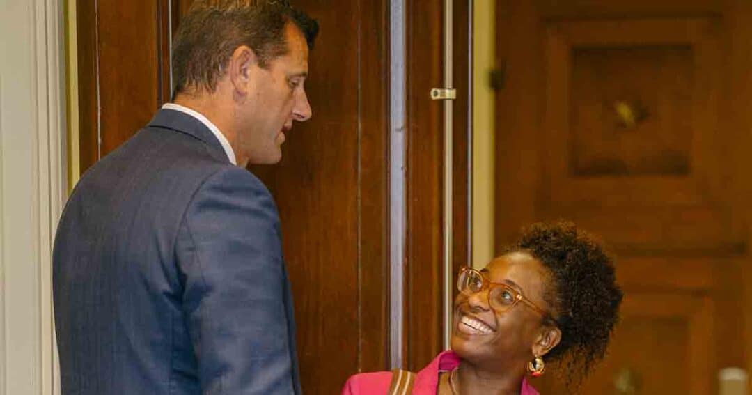 Allergy & Asthma Day Capitol Hill 2025: Leading the Charge Amid Federal Policy Shifts 14 A man in a blue suit stands by a doorway, talking with a smiling woman wearing glasses and a pink blazer. The woman looks up at him, and they appear to be having a friendly conversation indoors.