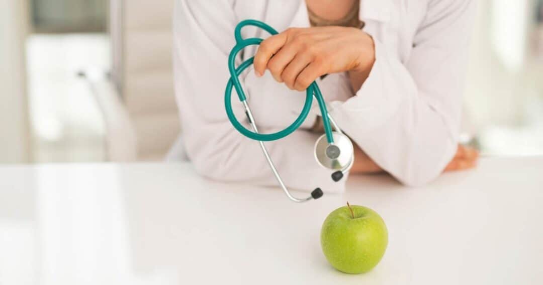 Alternative and Natural Asthma Treatments 1 A person in a white coat holding a stethoscope is leaning on a table. In front of them, there is a green apple on the table.