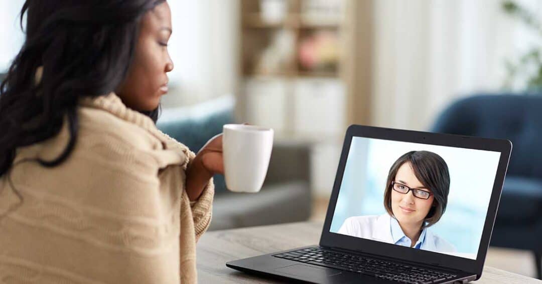 a women resting at home speaking to her online asthma coach on her laptop.