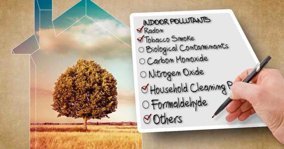 A hand holding a pen, checking off a list of indoor pollutants on a notepad, including radon, tobacco smoke, biological contaminants, carbon monoxide, nitrogen oxide, household cleaning products, formaldehyde, and others. Background shows a house outline and a tree.