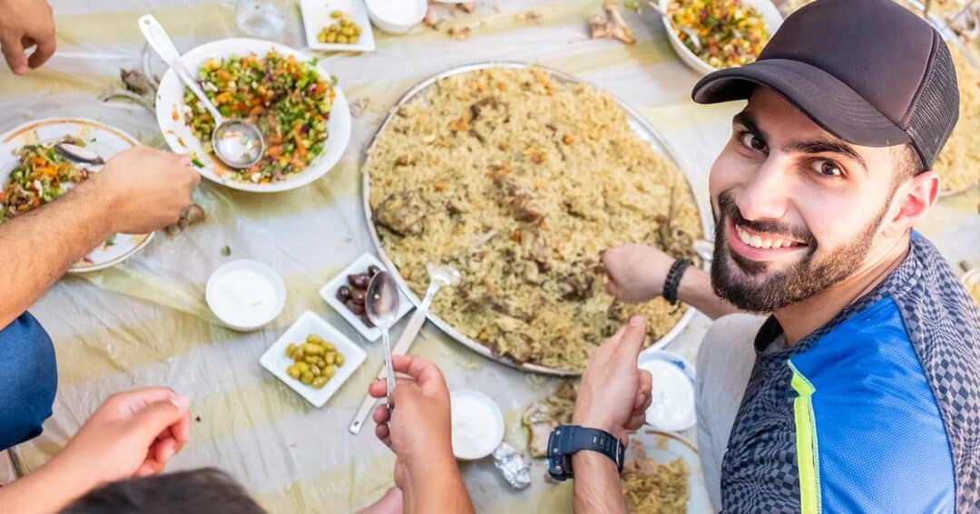 Happy Muslim man around table with his family, enjoying an ethnic meal cooked without food allergens.