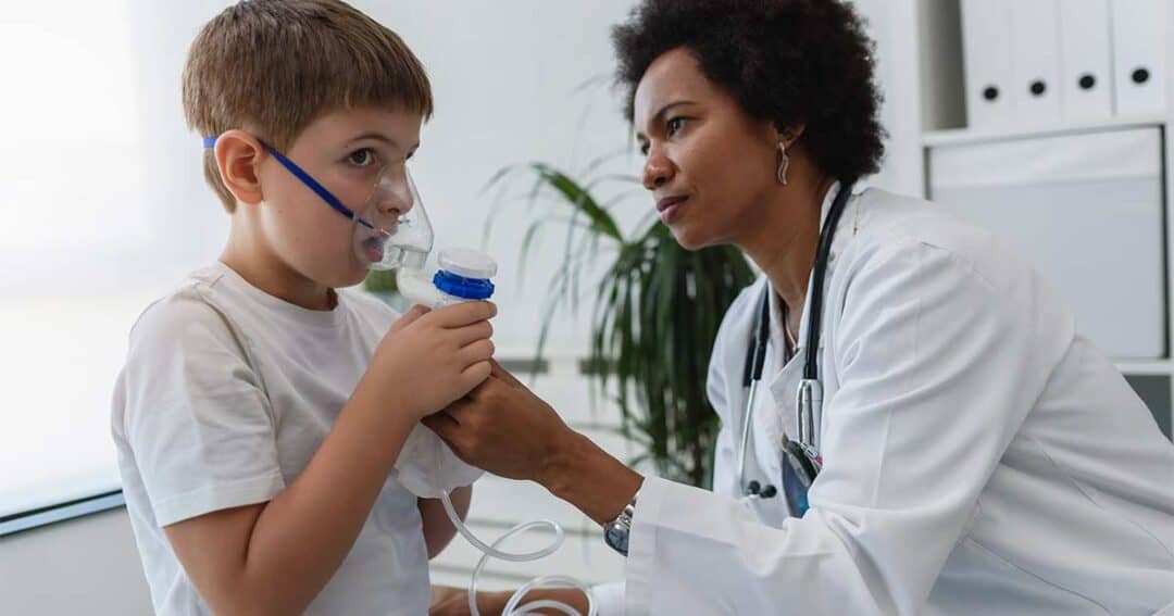 Doctor showing a boy how to use a nebulizer with a mask for asthma.