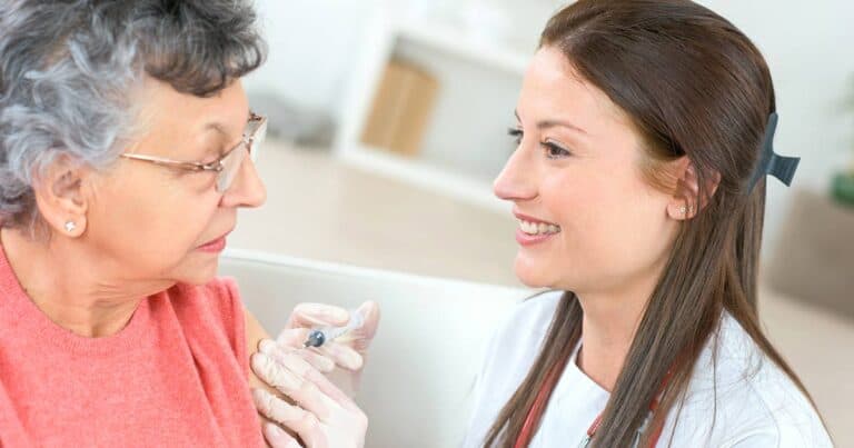 an elderly woman receiving her rsv shot by young nurse