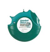 A green dental floss dispenser with a circular shape, featuring a split opening at the top and a central white label displaying text.