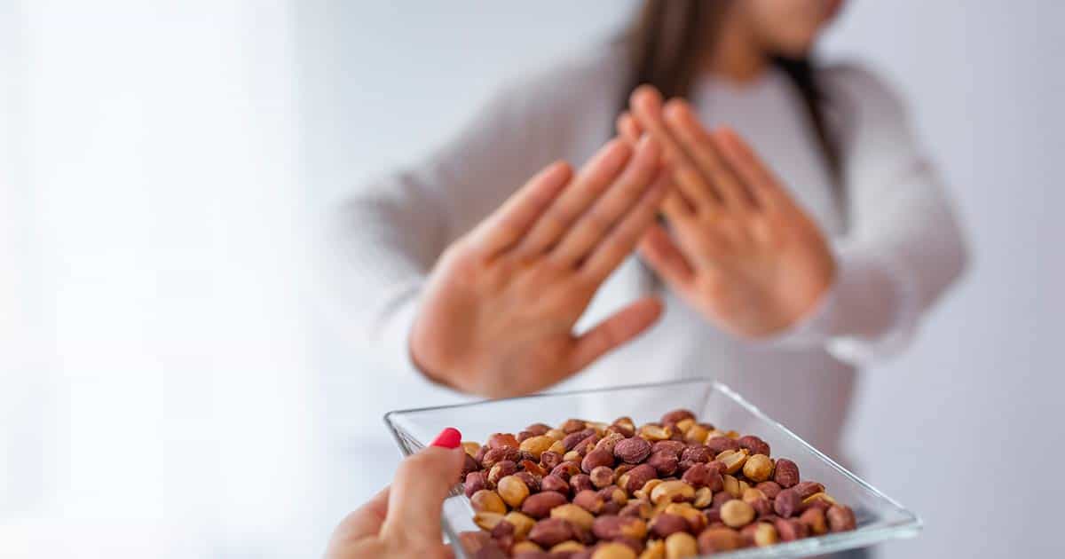 a woman with peanut allergy rejecting a bowl of peanuts