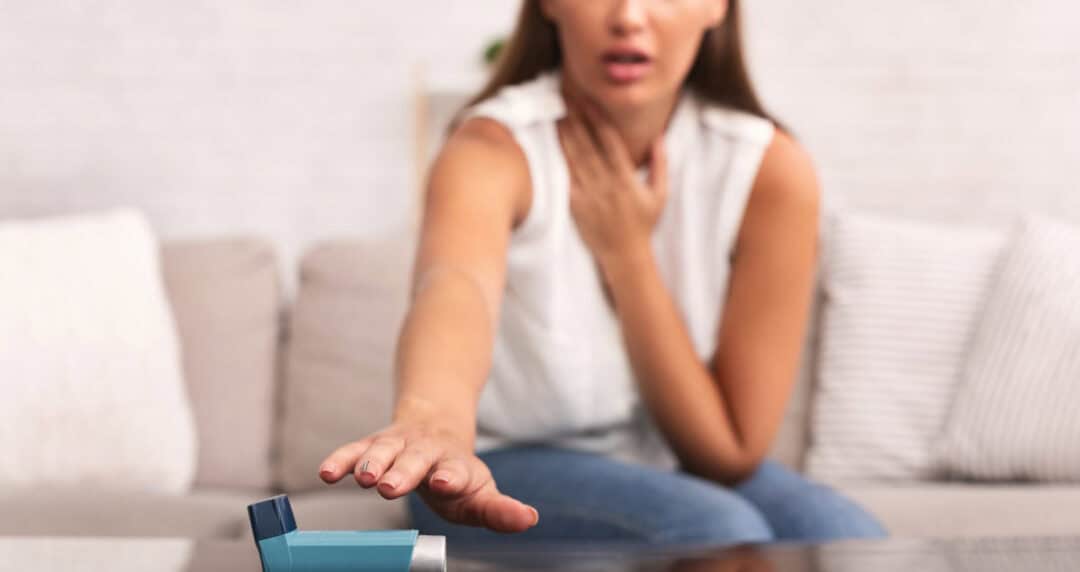 Girl Reaching For Asthma Inhaler Preventing Respiratory Depression Sitting On Couch At Home. Shallow Depth, Selective Focus