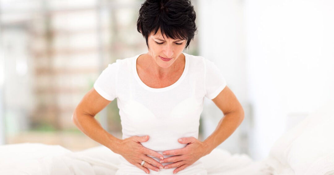 a woman with abdominal pain holds her stomach