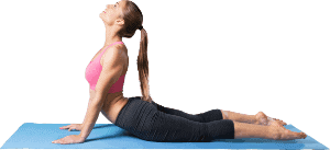 A woman practices yoga, performing the upward-facing dog pose on a blue mat. She wears a pink sports bra and black leggings, with her head tilted back and arms extended.
